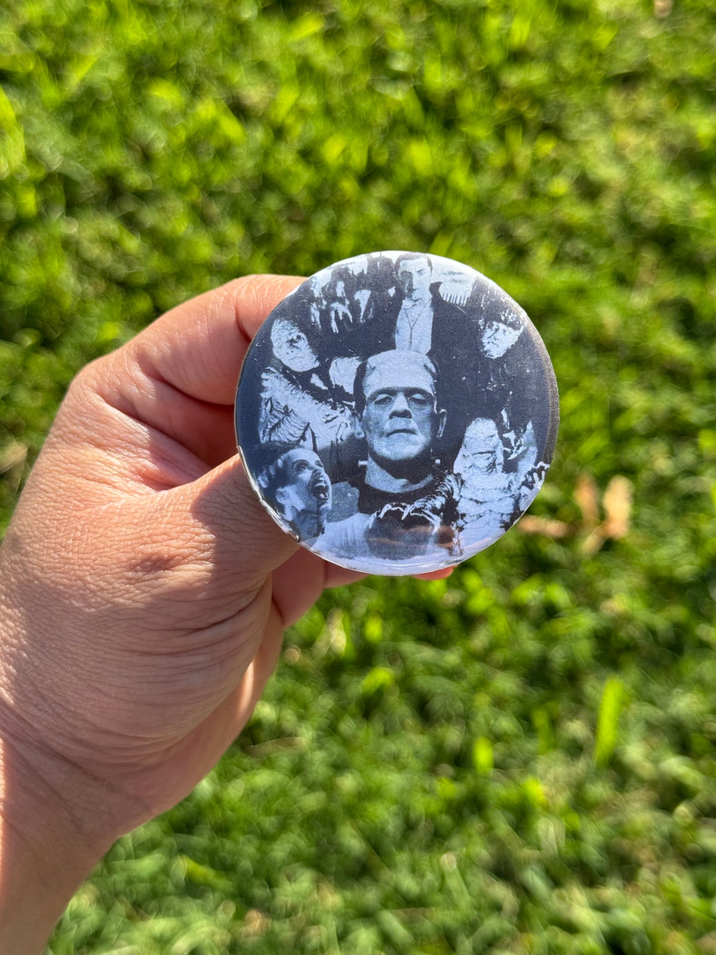 Button pin features images of characters from vintage horror movies: Frankenstein, Dracula, Bride of Frankenstein, Gill-man, Mummy, and more