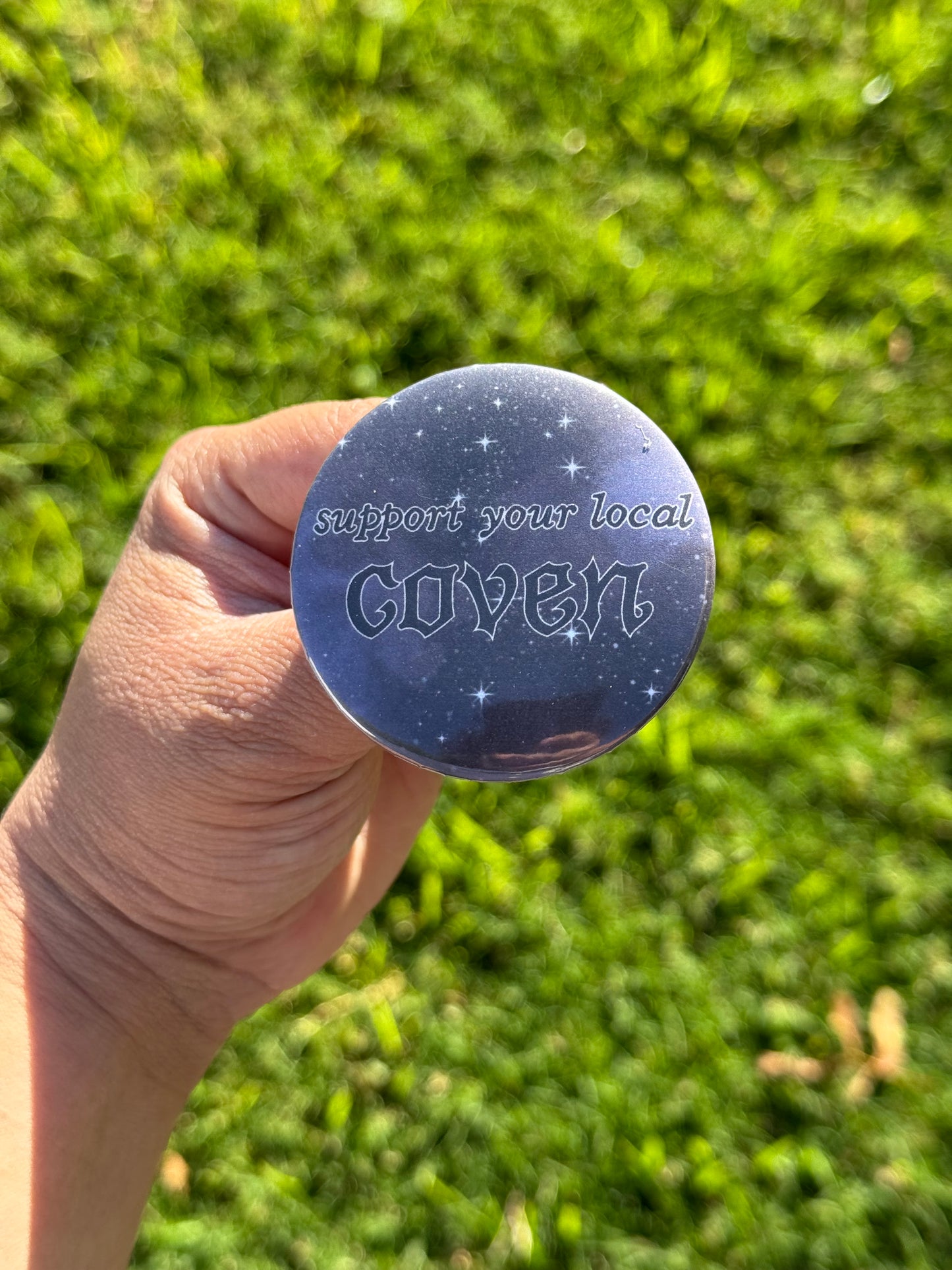 Button pin with starry background and text says “Support your local coven”